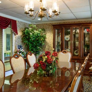 A luxurious dining room featuring an elegant chandelier, ornate wooden furniture, and a decorative floral centerpiece.