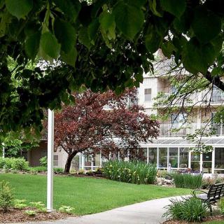 A scenic view of a garden with a pathway leading to a building, surrounded by lush greenery and trees.