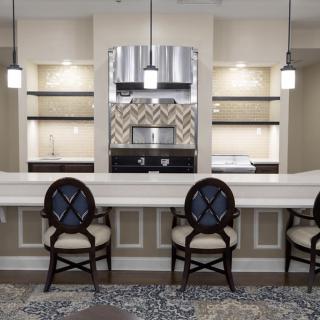 A modern kitchen with a sleek design featuring a large countertop, bar stools, and pendant lighting.