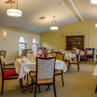 A spacious and elegantly designed dining room set up for a meal, featuring well-arranged tables and comfortable seating.