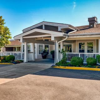 A welcoming entrance to a building with landscaped surroundings under a clear blue sky.