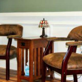 A cozy seating area with two upholstered chairs flanking a wooden side table and a decorative lamp.