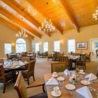 An elegant restaurant dining room with chandeliers and neatly set tables.