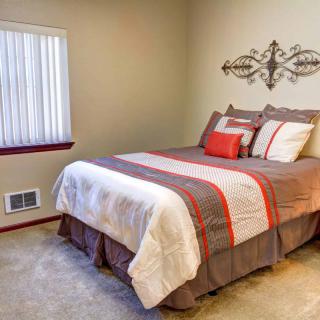A cozy bedroom with a neatly made bed and decorative pillows.