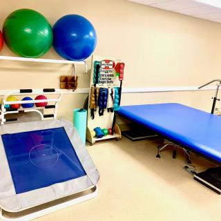 A well-equipped physical therapy room with exercise balls, a padded table, and various rehabilitation equipment.