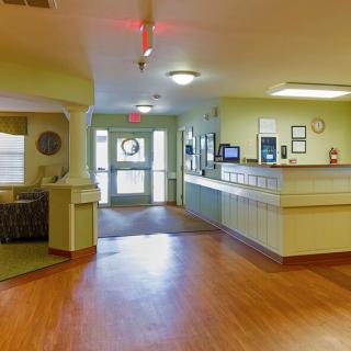 A view of a reception area with light green walls and wooden flooring.