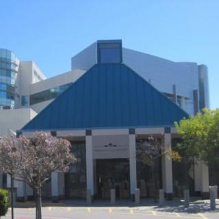 A modern building with a blue roof and glass elements in an urban setting.
