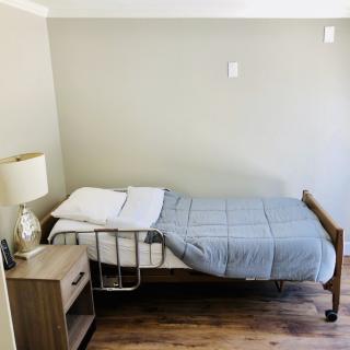 A simple bedroom with a single bed and nightstand.