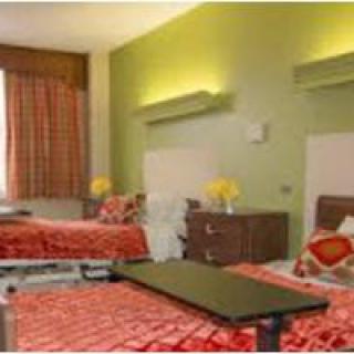 A hospital room with two neatly made twin beds and bright green walls.
