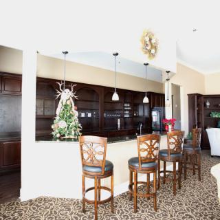 A modern kitchen with a countertop bar and bar stools, decorated for the holidays.