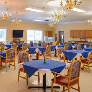 A well-lit dining room with blue tablecloths and elegant chandeliers.