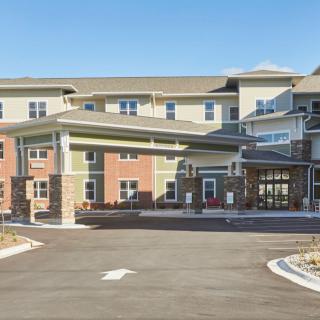 A modern residential building with a large entrance and driveway seen during the daytime.