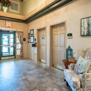 A cozy hallway featuring decorative artwork, seating, and two closed doors.