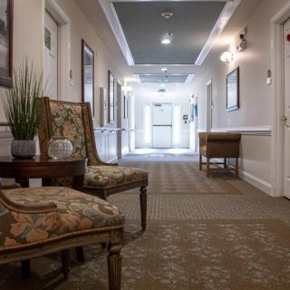 A well-lit hallway with elegant decor and seating arrangements.
