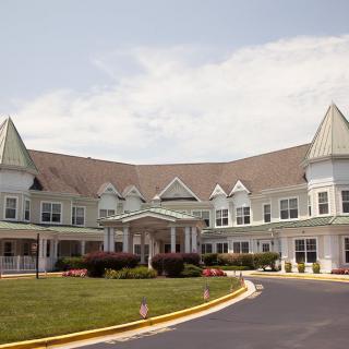 A large residential building with distinctive roofs and a landscaped driveway.