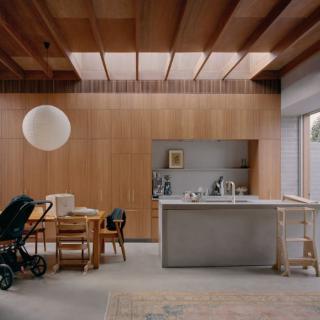 A modern kitchen and dining space with wooden interiors and a skylight.