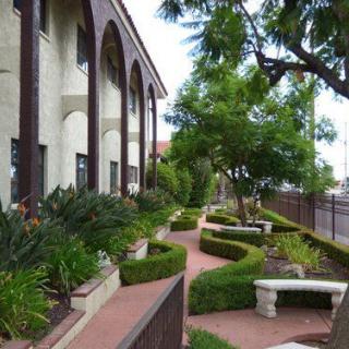 A beautifully landscaped area with a walkway, benches, and lush greenery alongside a building.