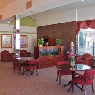 A cozy lobby area featuring seating arrangements with tables and chairs, an aquarium with plants, and decorative artwork on the walls.
