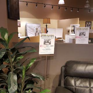 A cozy interior space featuring signage, a plant, and comfortable seating.
