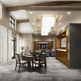 A modern lobby with a seating area featuring tables and chairs, accented by stylish lighting.