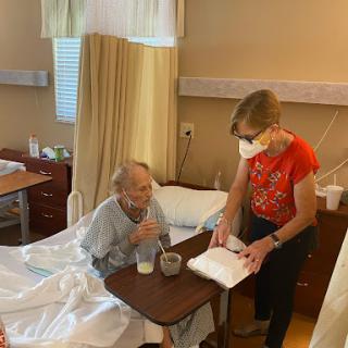 A caregiver provides support to a patient in a hospital room.