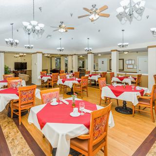 Elegantly set dining room with red tablecloths and stylish lighting.