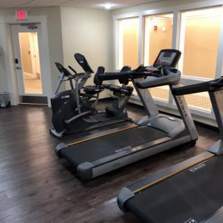 A gym room with treadmills and stationary bikes ready for use.