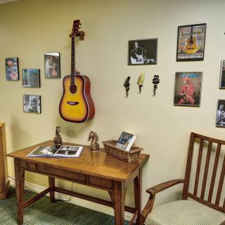 A cozy room with a music-themed decor featuring a guitar mounted on the wall and photographs displaying various musical artists.