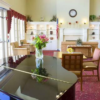 A cozy living room with a grand piano, floral arrangement, and elegant decor.