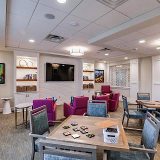 A modern lounge area with comfortable seating, a television, and bookshelves, accented by vibrant decor.