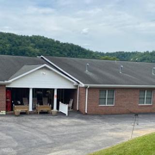 A brick residential building with a porch and mountain backdrop.