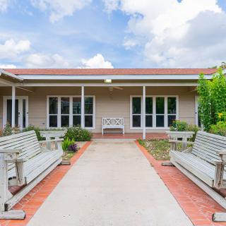 A serene courtyard with benches and a pathway leading to a building under a partly cloudy sky.