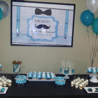 A beautifully decorated birthday party table set up for a boy, featuring teal balloons, cupcakes, and themed decorations.