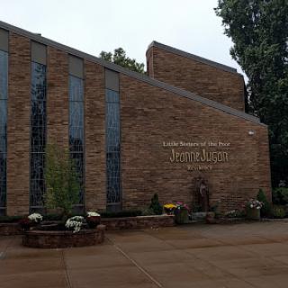 A brick church building with large windows and floral arrangements at the entrance.