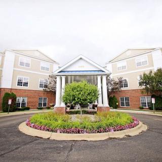 Front view of a residential building with a landscaped entrance and circular driveway.
