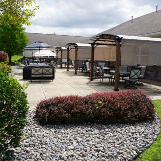 A well-maintained outdoor patio with seating areas and pergolas, surrounded by a landscaped garden.