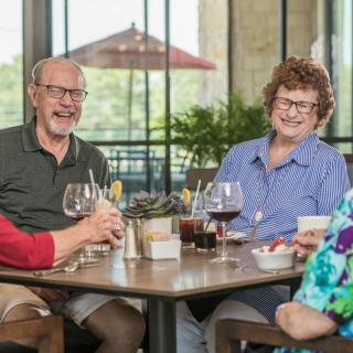 A group of seniors enjoying a social gathering at a restaurant, sharing laughter and drinks.