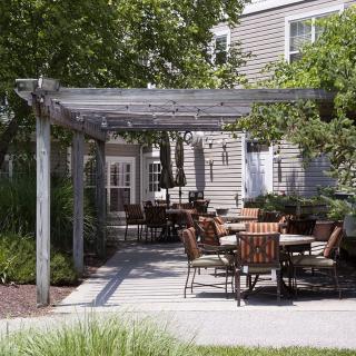 Outdoor patio area with chairs and tables under a pergola.