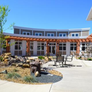 A modern building with a garden and patio area featuring a pergola.