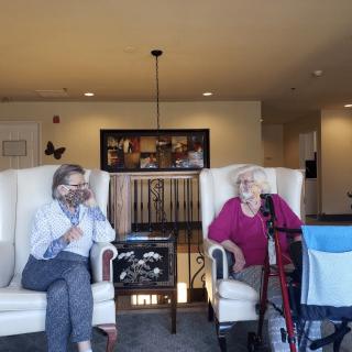 Two elderly individuals sitting in a living room having a conversation.