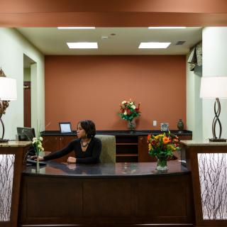 A receptionist sits at the front desk in a well-decorated office lobby.