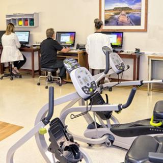 Healthcare professionals working in a rehabilitation center equipped with gym machines.