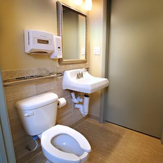A clean and modern bathroom featuring a toilet, sink, mirror, and hand dryer.