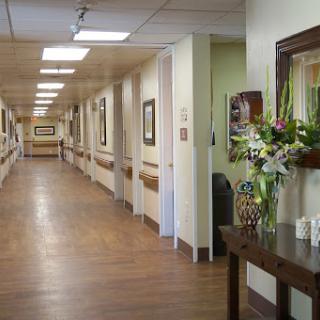 A well-lit corridor in a healthcare facility adorned with artwork and flowers.