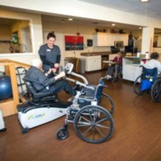 Individuals in wheelchairs engaged in physical therapy exercises at a rehabilitation center.