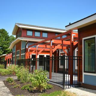 A modern building with redwood design elements and large windows surrounded by neatly maintained landscaping.