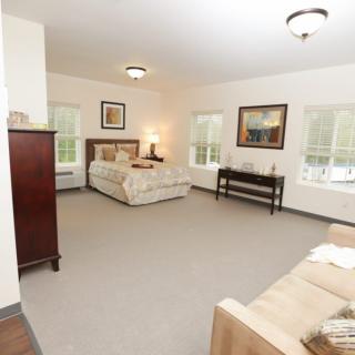 A spacious bedroom with elegant furniture and large windows.