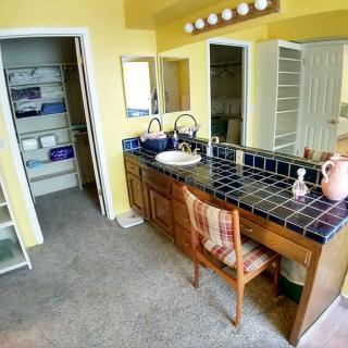 Spacious bathroom with a tile-top vanity and an adjacent closet.