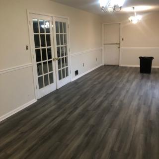 A modern empty room with hardwood flooring and French doors.