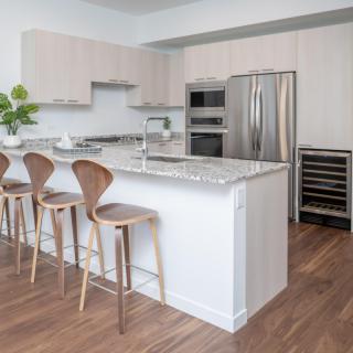 A modern kitchen with a large island, bar stools, and stainless steel appliances.